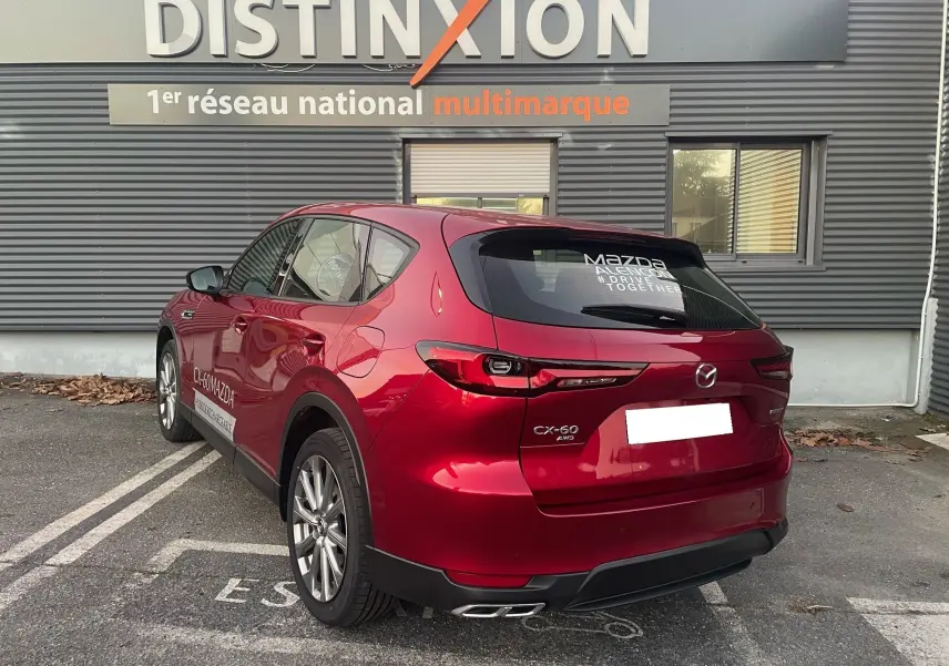 Vue 3/4 arrière droite d'un Mazda CX-60 Soul Red Crystal garé devant un bâtiment Distinxion.