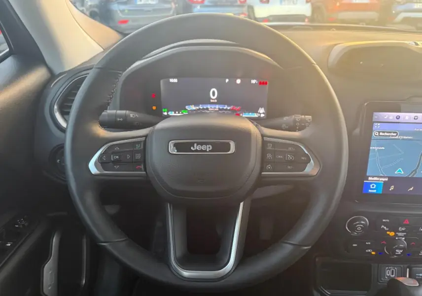 Vue centrée sur le volant Jeep noir avec tableau de bord numérique et écran tactile GPS du Renegade 2024.