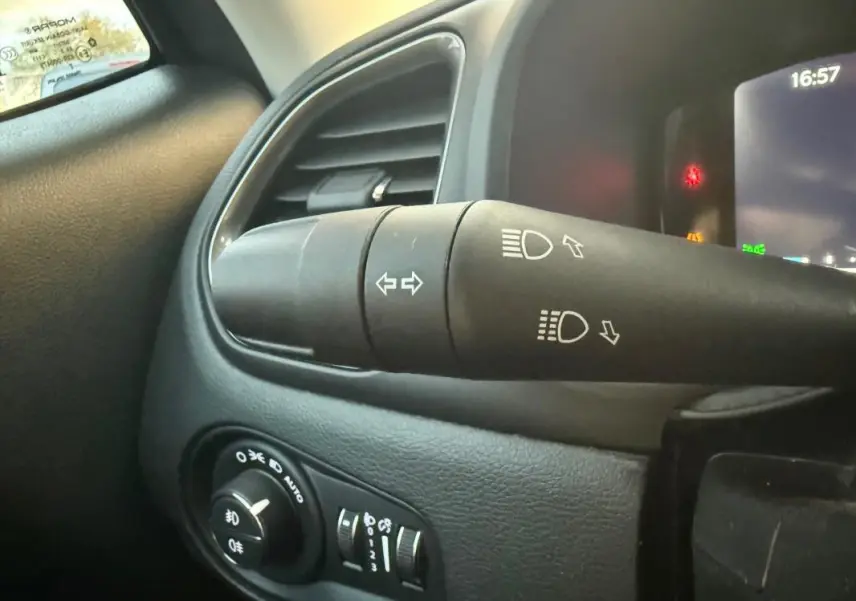 Gros plan sur la commande des phares et clignotants à gauche du volant dans l'habitacle d'un Jeep Renegade gris anthracite 2024.