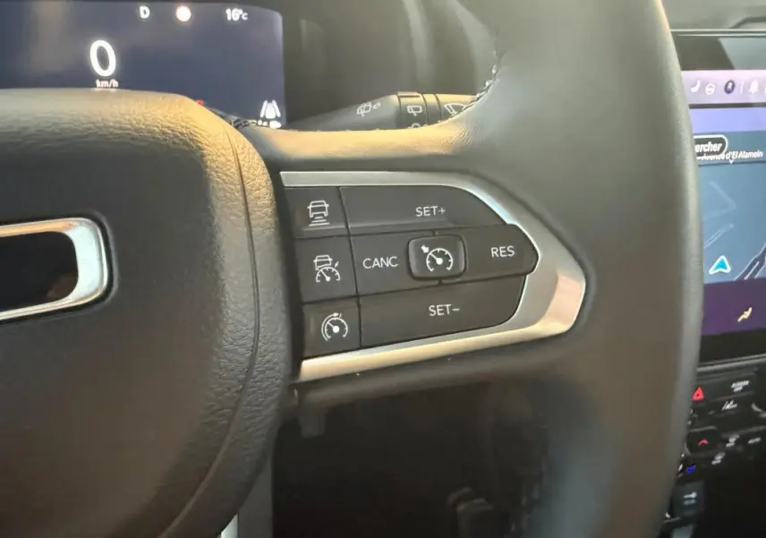 Gros plan sur les commandes du régulateur de vitesse au volant cuir noir du Jeep Renegade 2024 e-Hybrid Summit.