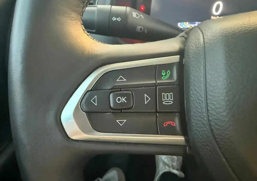 Gros plan sur les commandes du volant à gauche du Jeep Renegade 2024 gris anthracite, boutons de téléphone et navigation.