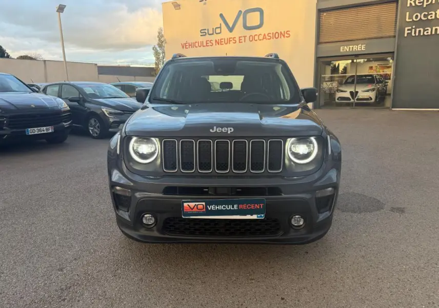 Vue frontale d'un Jeep Renegade gris anthracite 2024 avec phares allumés et calandre distinctive à sept fentes.