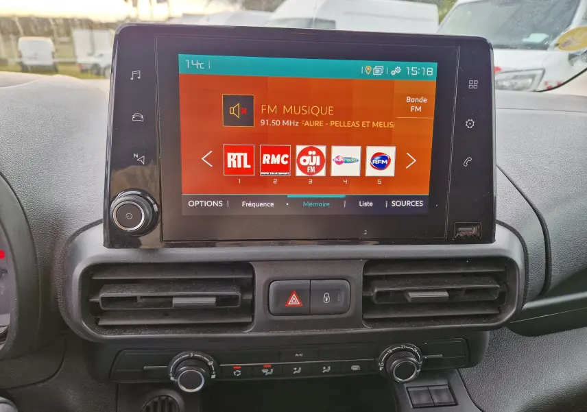 Vue rapprochée de l’écran tactile central du tableau de bord du Citroën Berlingo blanc 2021 affichant les stations radio FM.