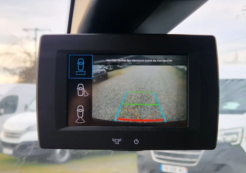Écran de caméra de recul dans un Citroën Berlingo blanc, vue intérieure centrée sur l'affichage des aides au stationnement.