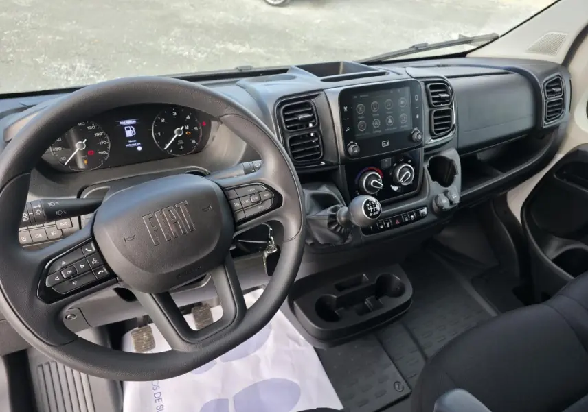 Vue intérieure du poste de conduite du Fiat Ducato Fourgon blanc, avec volant multifonction et écran tactile central 7 pouces.