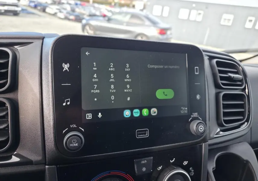 Écran tactile 7 pouces du tableau de bord du Fiat Ducato Fourgon blanc, avec commandes multimédia et climatisation.