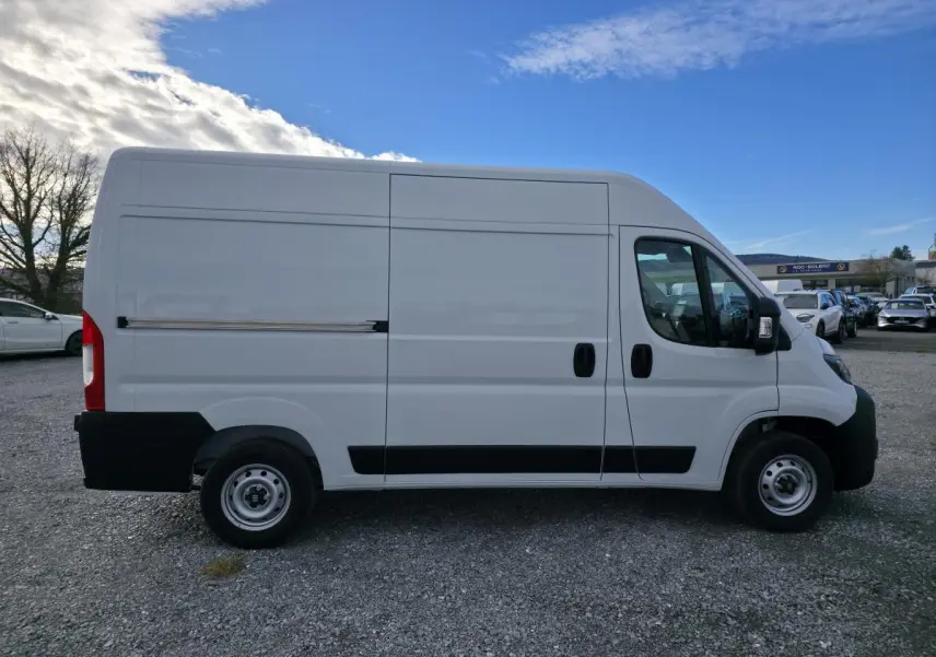 Fiat Ducato Fourgon blanc vu de profil côté gauche, avec porte latérale coulissante tôlée et roues acier.
