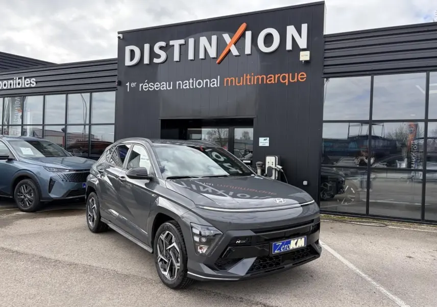 Hyundai KONA II 1.6 Hybrid N Line gris Ecotronic en 3/4 avant droit devant un showroom Distinxion.