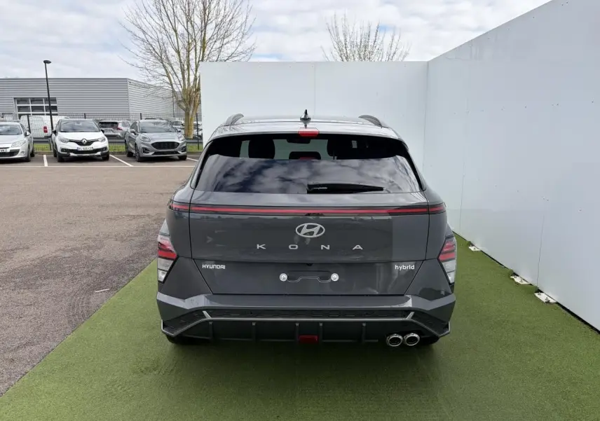 Vue arrière d'un Hyundai Kona 2 hybride gris métallisé avec feux arrière LED et double sortie d'échappement chromée.
