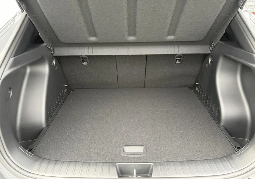 Coffre ouvert vu de l'arrière du Hyundai Kona II 1.6 Hybrid N Line gris Ecotronic, montrant un espace de chargement propre et spacieux.