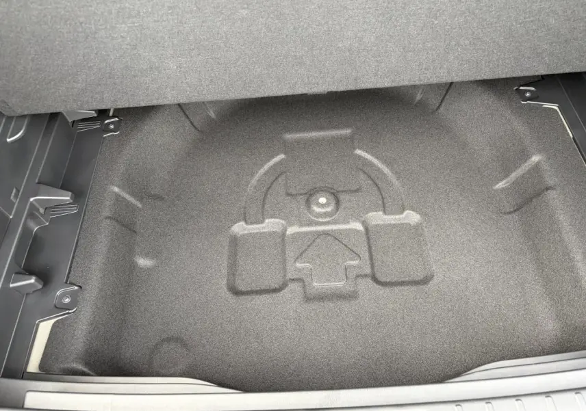 Coffre ouvert du Hyundai Kona 2026 gris Ecotronic, vue plongeante sur le rangement sous plancher sans roue de secours.