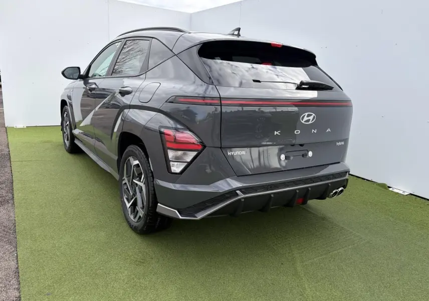 Vue 3/4 arrière droite du Hyundai KONA II hybride en gris métallisé Ecotronic, avec feux arrière LED et double sortie d'échappement.