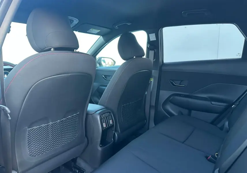 Vue intérieure arrière du Hyundai Kona II gris, montrant les sièges arrière et les dossiers des sièges avant avec prises USB-C.