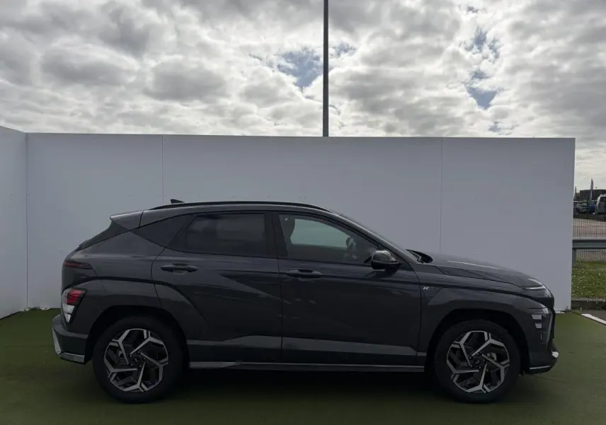 Vue de profil côté gauche d'un Hyundai Kona II 1.6 Hybrid N Line gris métallisé Ecotronic avec jantes alliage 18 pouces.