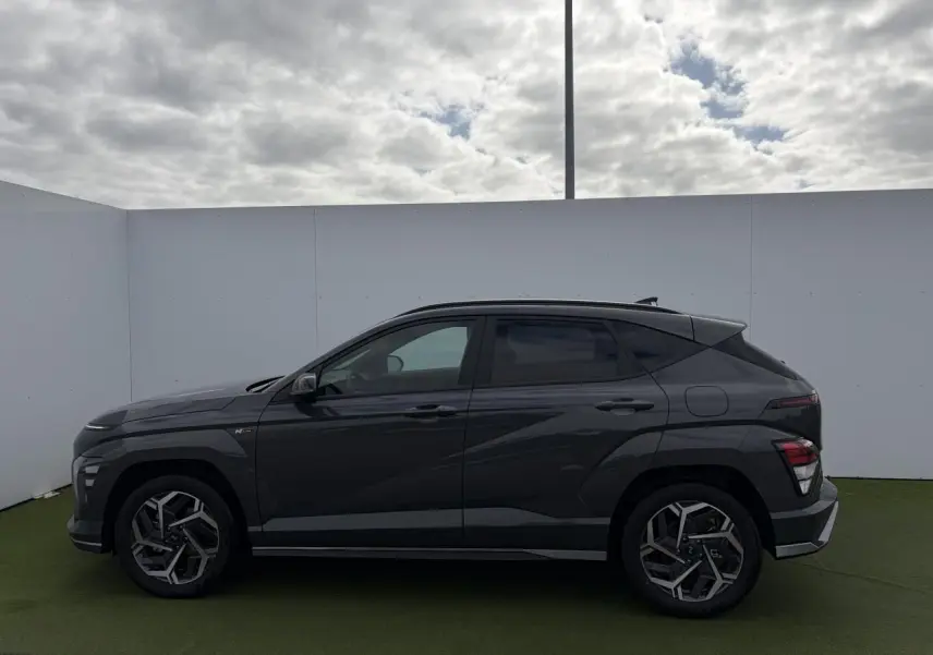 Vue latérale droite d'un Hyundai Kona II 1.6 Hybrid N Line 2026 en gris métallisé Ecotronic avec jantes alliage 18 pouces.