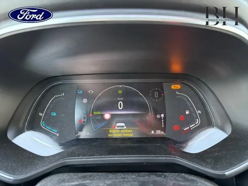 Tableau de bord numérique de Renault Clio blanc, affichant vitesse zéro et alertes de ceinture et moteur.