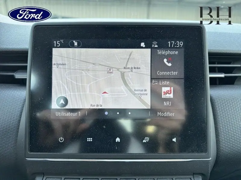 Écran tactile central de la Renault Clio blanche 2021 affichant la navigation GPS et les options téléphone en intérieur.