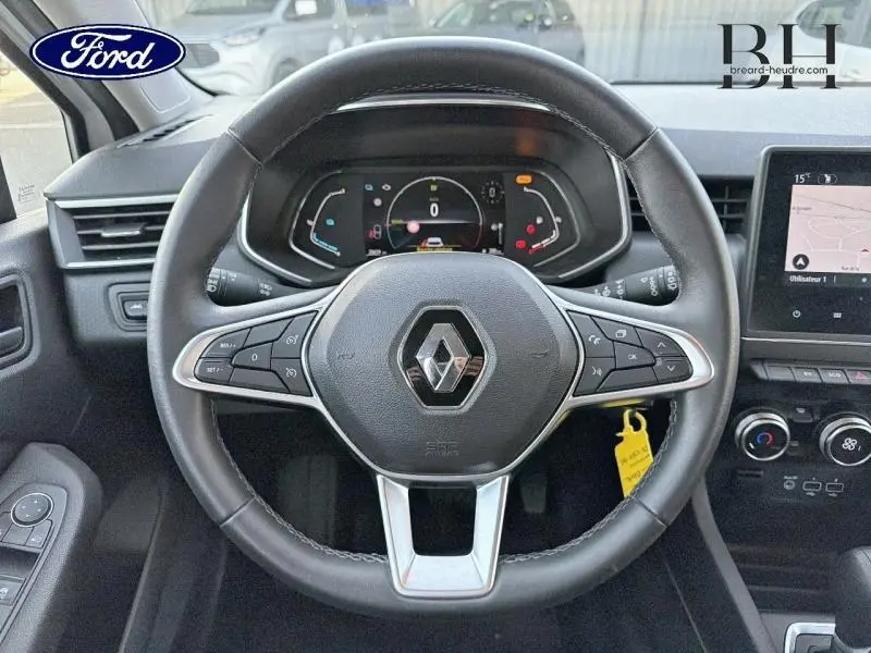 Vue rapprochée du volant noir de la Renault Clio 1.6 E-Tech 140ch avec tableau de bord numérique et écran tactile.