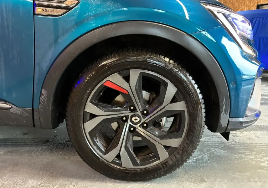 Gros plan sur la roue avant droite d’un Renault Arkana bleu 1.3 TCE 140 RS-LINE avec jante alliage et détail rouge.