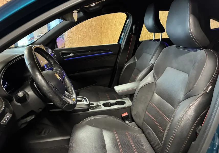 Vue intérieure côté conducteur du Renault Arkana bleu 2021, sièges noirs en cuir avec surpiqûres rouges et volant multifonction.