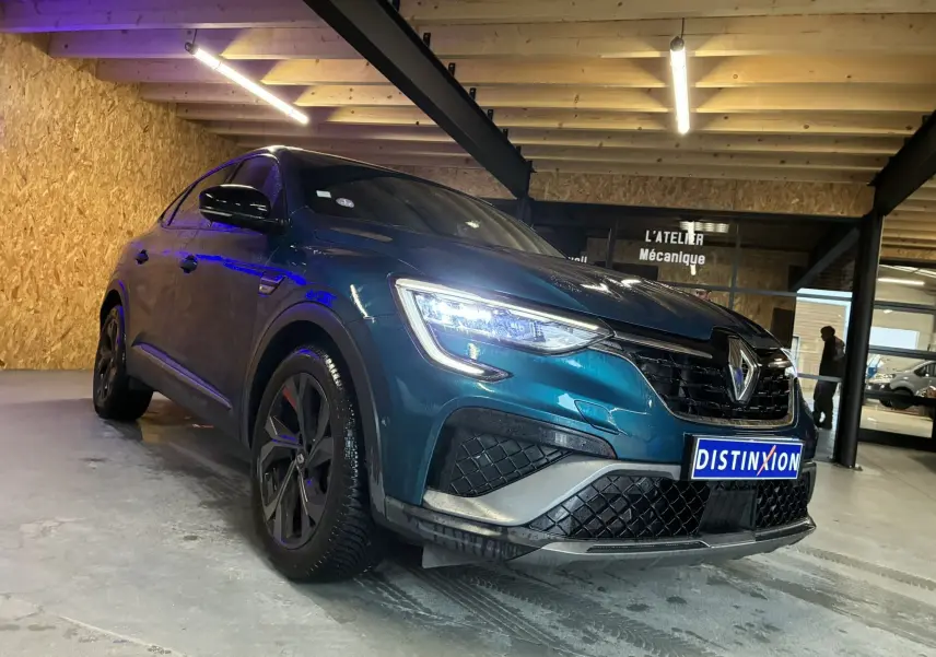 Renault Arkana 1.3 TCE 140 RS-Line bleu en 3/4 avant droit, avec phares LED allumés dans un garage.