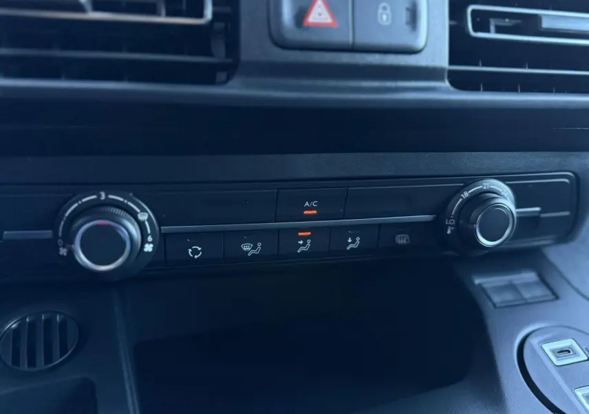 Gros plan sur la console centrale noire du Peugeot Partner 2026 avec commandes climatisation et ventilation.