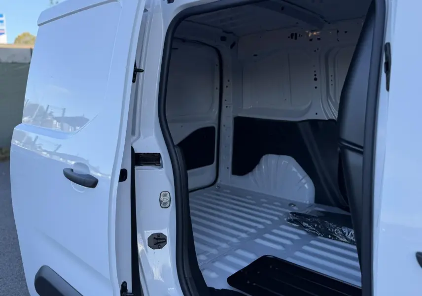 Vue latérale gauche sur l'ouverture de la porte coulissante d'un Peugeot Partner blanc Icy, montrant l'intérieur vide du coffre.