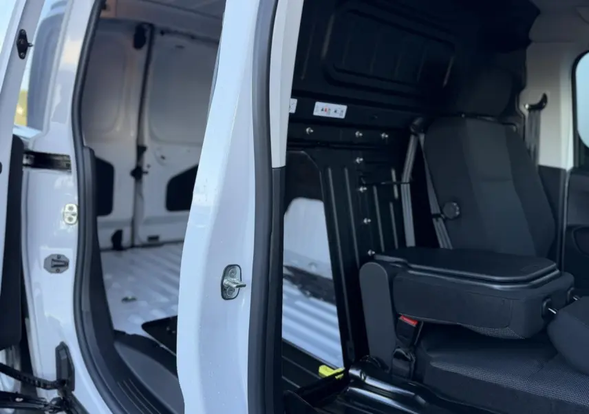 Vue intérieure côté droit du Peugeot Partner blanc Icy 2026 avec porte coulissante ouverte et banquette passager rabattue.