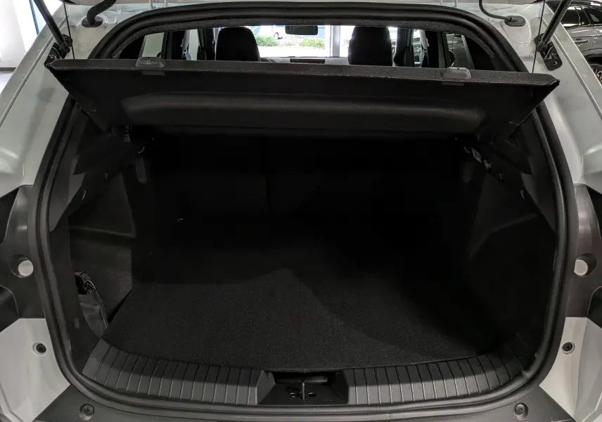 Coffre ouvert vu de l’arrière d’un Dacia Duster blanc Glacier, montrant l’espace de chargement et la plage arrière.