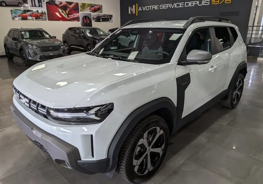 Vue 3/4 avant droite du Dacia Duster Hybrid-G blanc Glacier avec jantes bi-ton et éléments noirs contrastants.