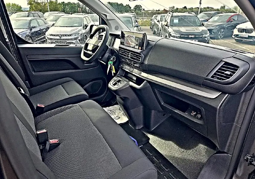 Vue intérieure côté conducteur du Fiat Scudo Combi 2026, sièges bi-ton noir/gris et tableau de bord moderne avec écran tactile.