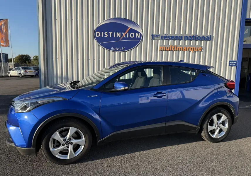Profil côté gauche d'un Toyota C-HR bleu Nebula Hybrid 2018 avec jantes alliage et détails noirs contrastants.
