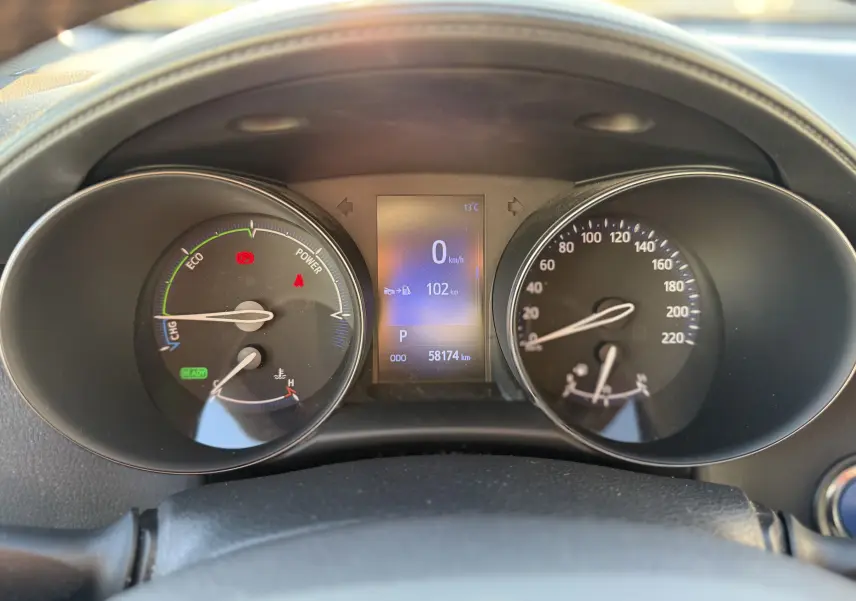 Vue rapprochée du tableau de bord du Toyota C-HR hybride bleu Nebula, affichant la vitesse à zéro et 58 174 km au compteur.
