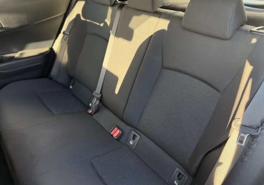 Vue rapprochée des sièges arrière en tissu noir du Toyota C-HR 1.8 Hybrid 2018, éclairage naturel sur la droite.