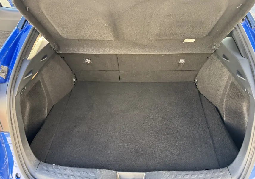 Coffre ouvert d'un Toyota C-HR 1.8 Hybrid bleu Nebula, montrant un espace de chargement propre et spacieux.