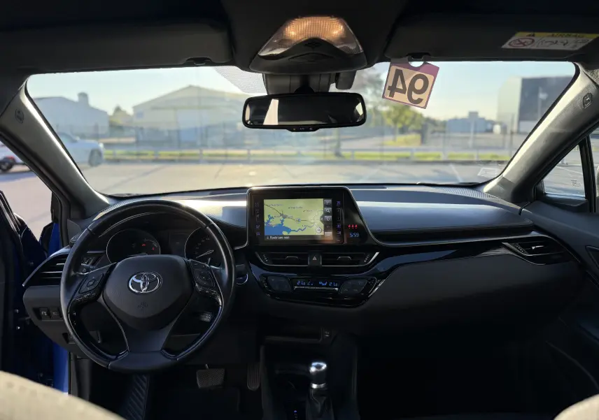 Vue intérieure frontale du Toyota C-HR bleu Nebula Hybrid 2018, avec tableau de bord et écran tactile GPS allumé.