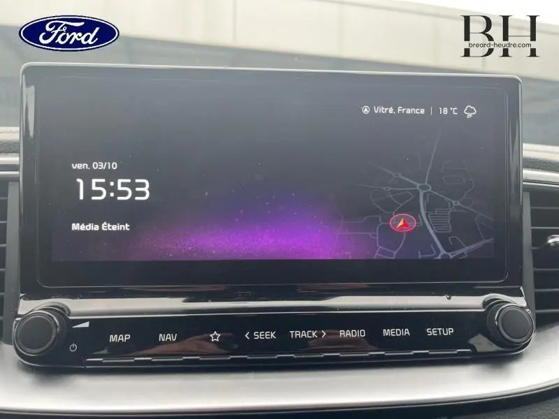 Écran tactile central affichant l'horloge et la carte GPS dans un véhicule noir, vue de face rapprochée.