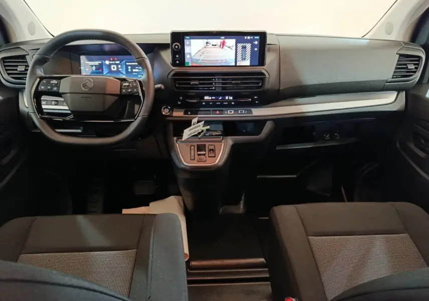Vue intérieure avant du Citroën Jumpy XL 2025 noir, tableau de bord avec écran tactile et volant multifonction.