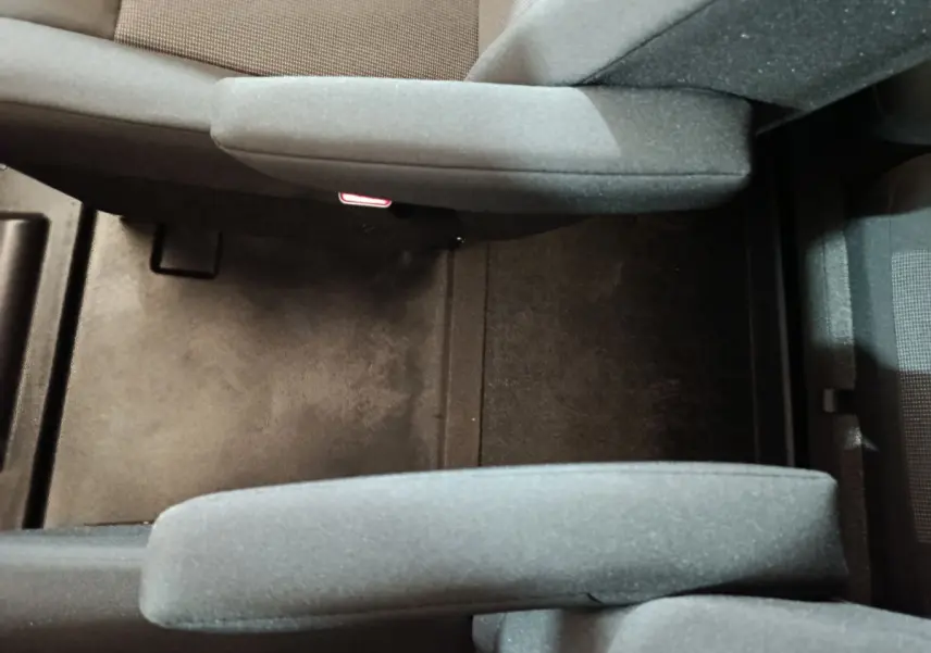 Vue plongeante sur l'espace entre les sièges avant gris foncé du Citroën Jumpy XL 2025, tissu et moquette noire.