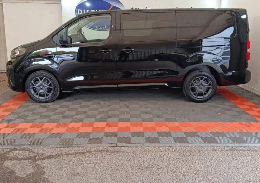 Profil droit d'un Citroën Jumpy XL noir 2025 avec jantes spécifiques et cloison vitrée visible à l'arrière.