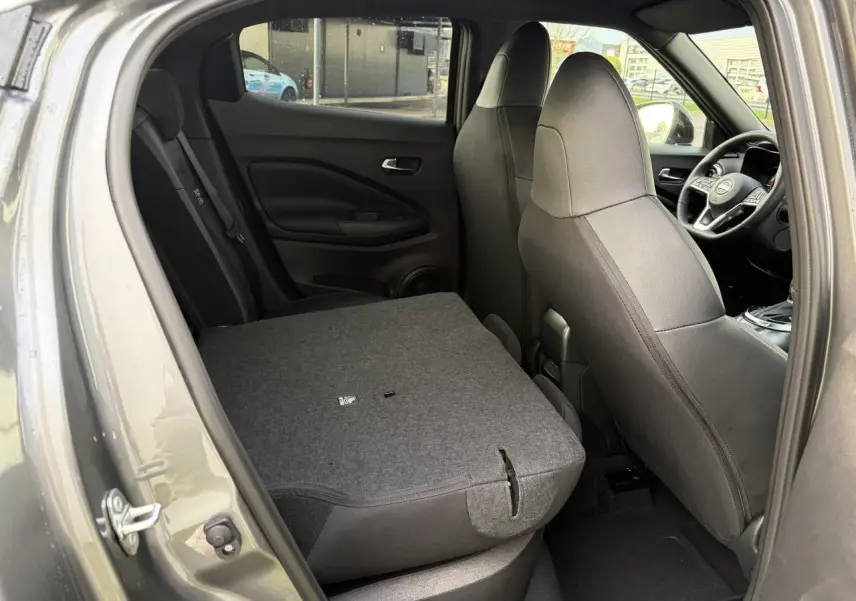 Vue intérieure côté gauche du Nissan Juke II 1.6 Hybrid 2025 noir métal avec banquette arrière rabattue.