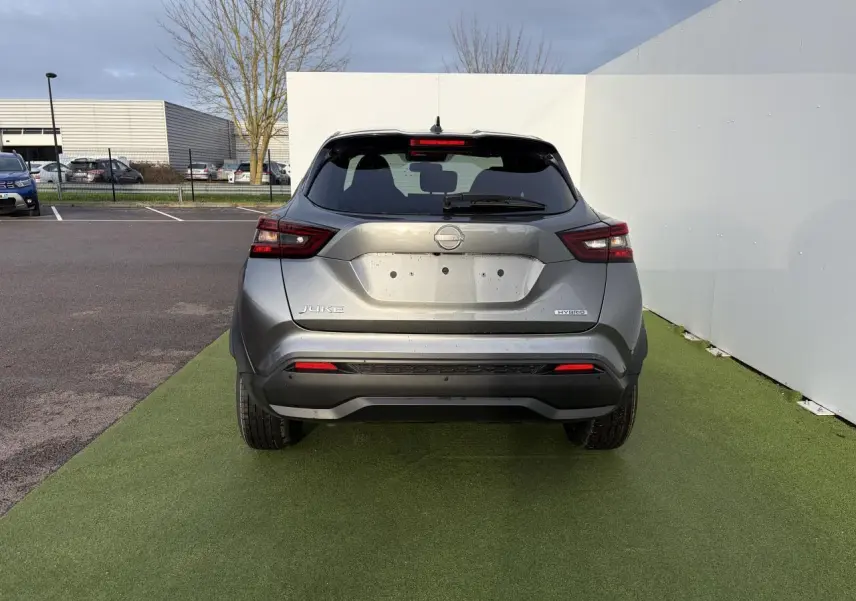 Vue arrière d'un Nissan Juke II hybride gris métallisé avec feux LED et antenne aileron de requin noire.