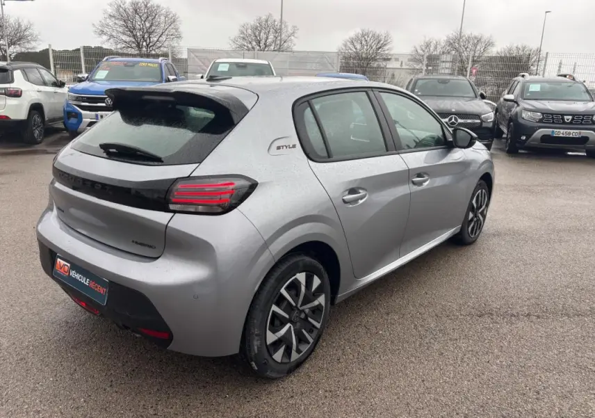 Vue 3/4 arrière droite d'une Peugeot 208 Hybrid grise 2025 avec jantes 16 pouces et badge Style sur le côté.