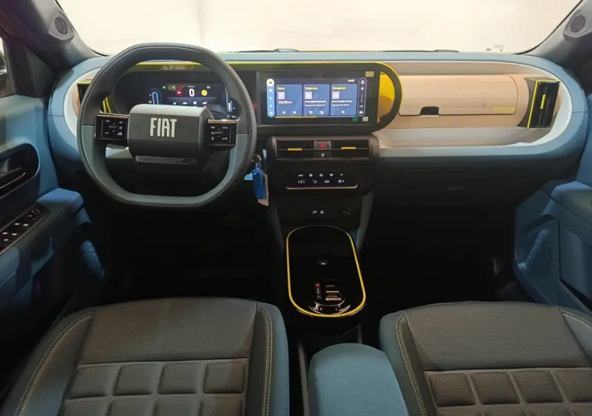 Intérieur avant de la Fiat Grande Panda jaune 2025, tableau de bord moderne avec écran tactile et volant multifonctions.