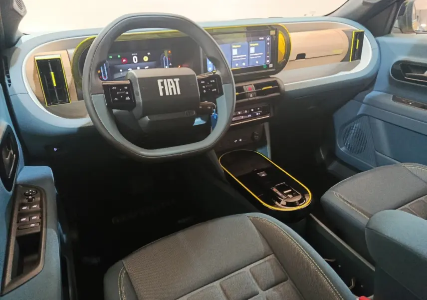 Vue intérieure avant droite de la Fiat Grande Panda 1.2 Hybrid 2025, tableau de bord beige et bleu avec écran tactile et volant carré.