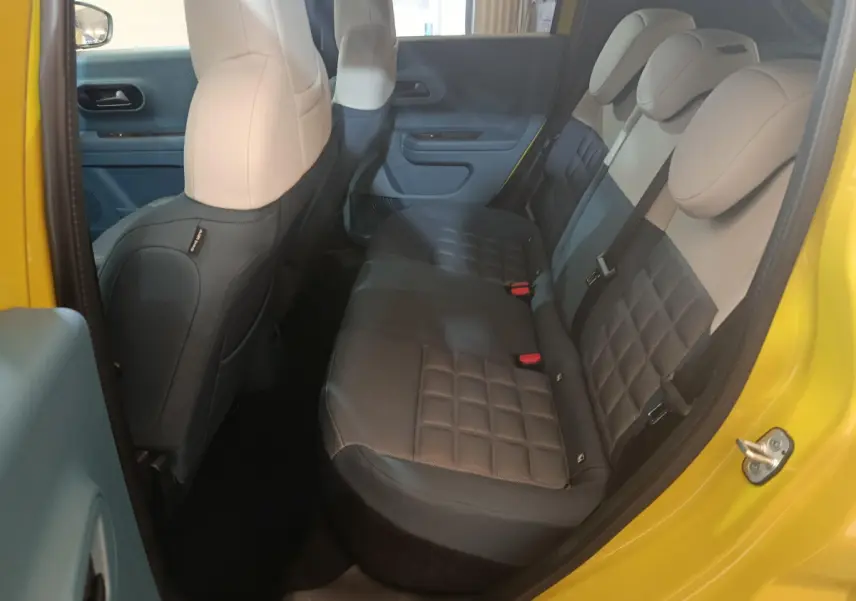 Vue intérieure côté droit de la banquette arrière bicolore beige et noir d'une FIAT Grande Panda jaune 2025.
