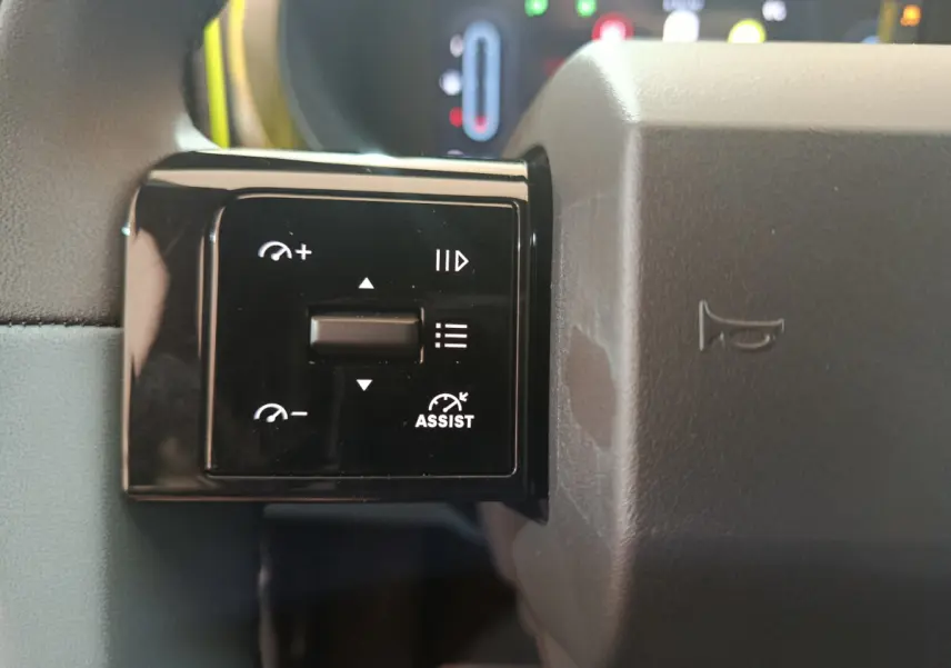 Gros plan sur les commandes de régulateur de vitesse au volant gris de la FIAT Grande Panda jaune.