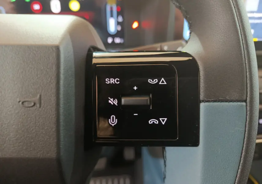 Gros plan sur les commandes vocales et volume au volant cuir bleu de la FIAT Grande Panda jaune 2025.