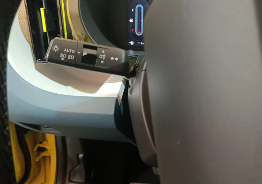 Détail du commodo d'éclairage côté gauche dans l'habitacle jaune vif d'une Fiat Grande Panda 2025.