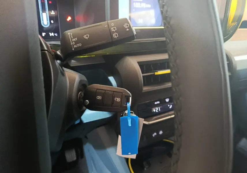 Gros plan intérieur sur le volant et la clé de la Fiat Grande Panda jaune, avec tableau de bord et commandes visibles.